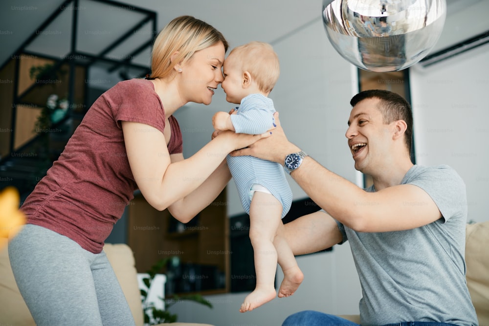 Young happy parents having fun with their baby son at home.