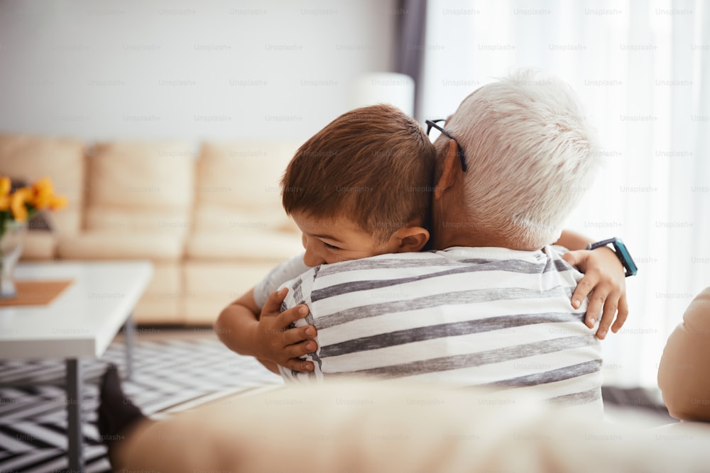 Liebevoller Großvater und Enkel genießen, während sie sich zu Hause umarmen.
