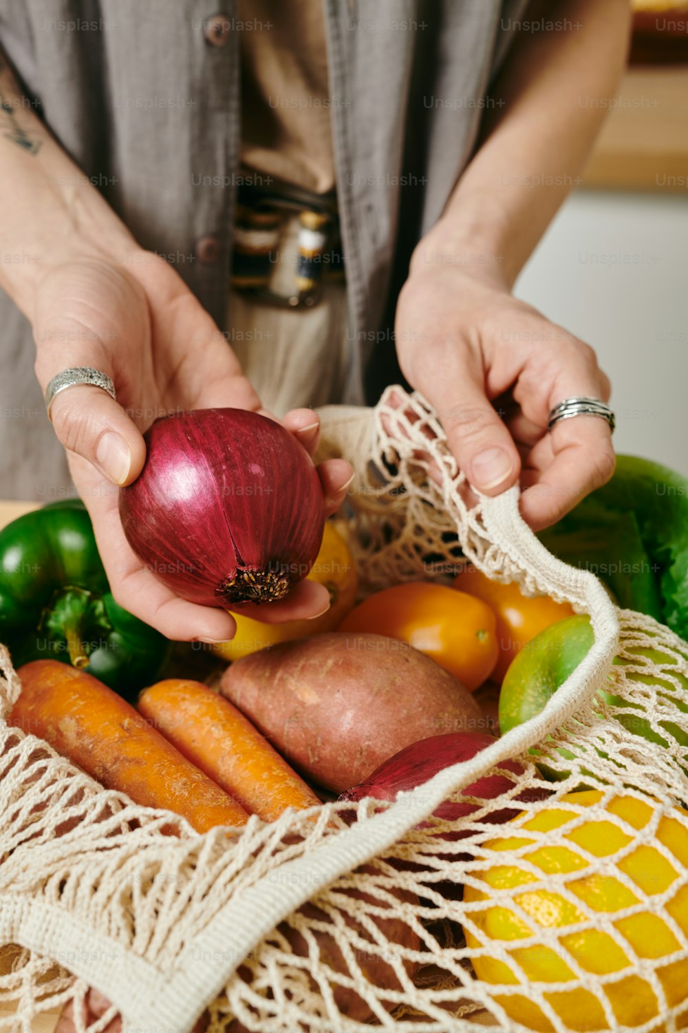 Mujer vegetariana sosteniendo cebolla fresca sobre bolsa con otras verduras