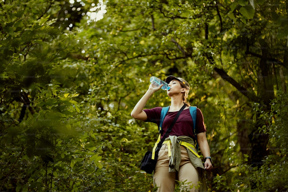 Young woman refreshing herself with water while hiking in nature,