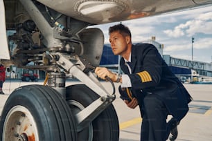 Jovem aviador focado vestido com uniforme realizando uma inspeção visual de um veículo aéreo