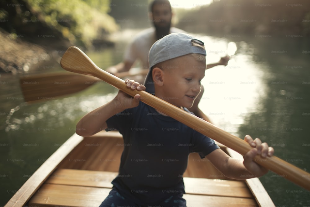 Boy learning to paddle canoe with his father on a beautiful sunny day.