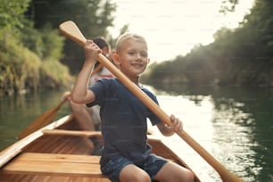 Boy learning to paddle canoe with his father on a beautiful sunny day.