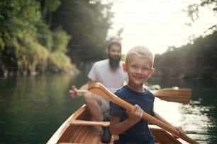 Ragazzo che impara a pagaiare in canoa con suo padre in una bella giornata di sole.
