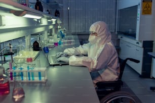 Disabled female researcher in protective workwear using laptop