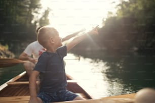 Boy learning to paddle canoe with his father on a beautiful sunny day.