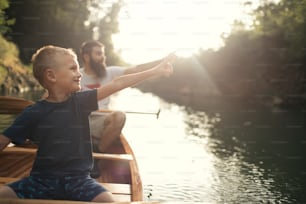 Boy learning to paddle canoe with his father on a beautiful sunny day.