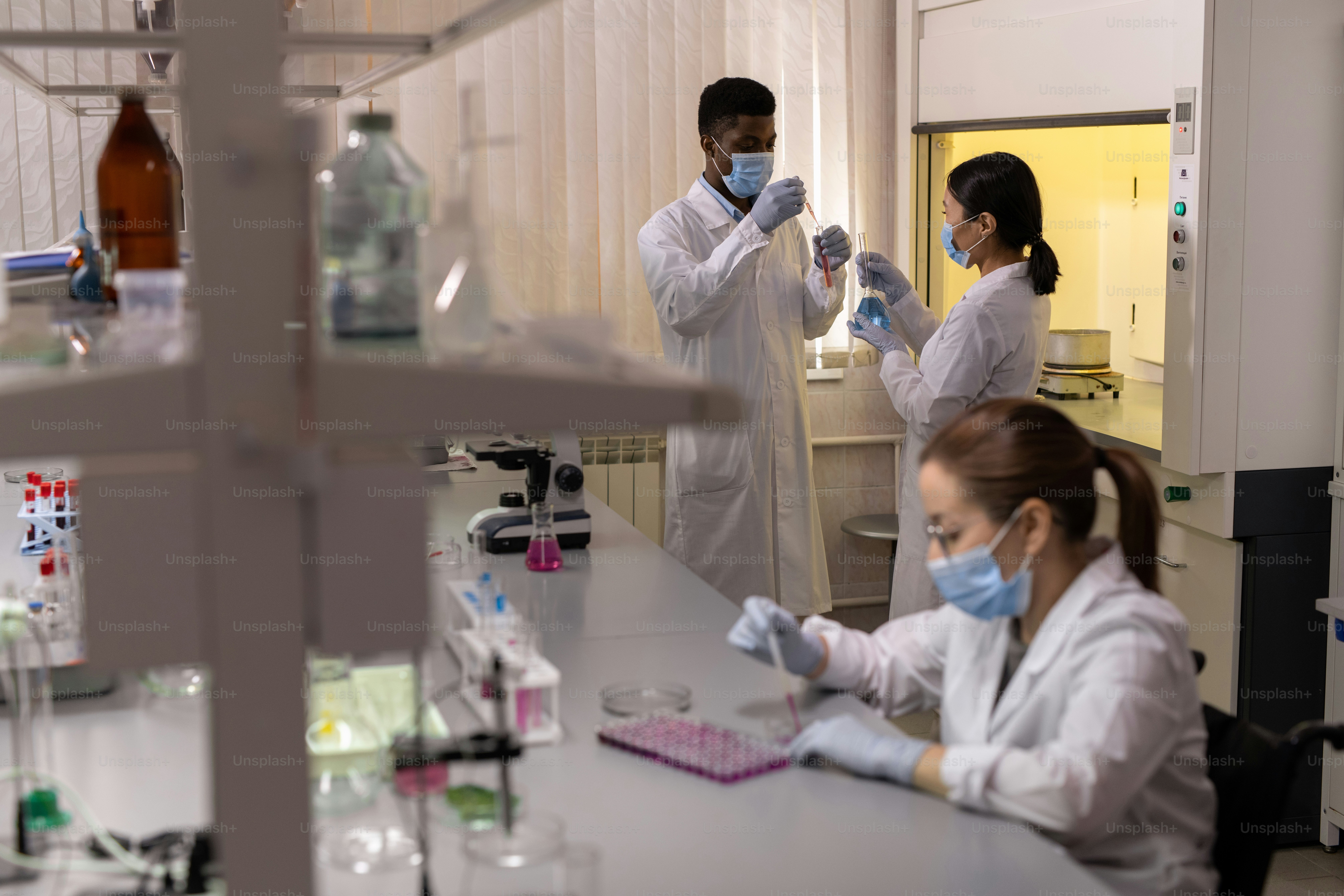 Gruppe junger Wissenschaftler, die im wissenschaftlichen Labor mit Flüssigkeiten in Flaschen arbeiten