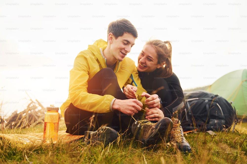 Young lovely couple sitting near tent outdoors at daytime. Beautiful sunlight.