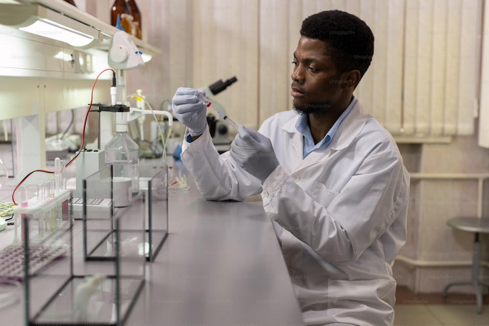 Joven científico africano que toma una nueva vacuna en una jeringa antes de hacer la inyección
