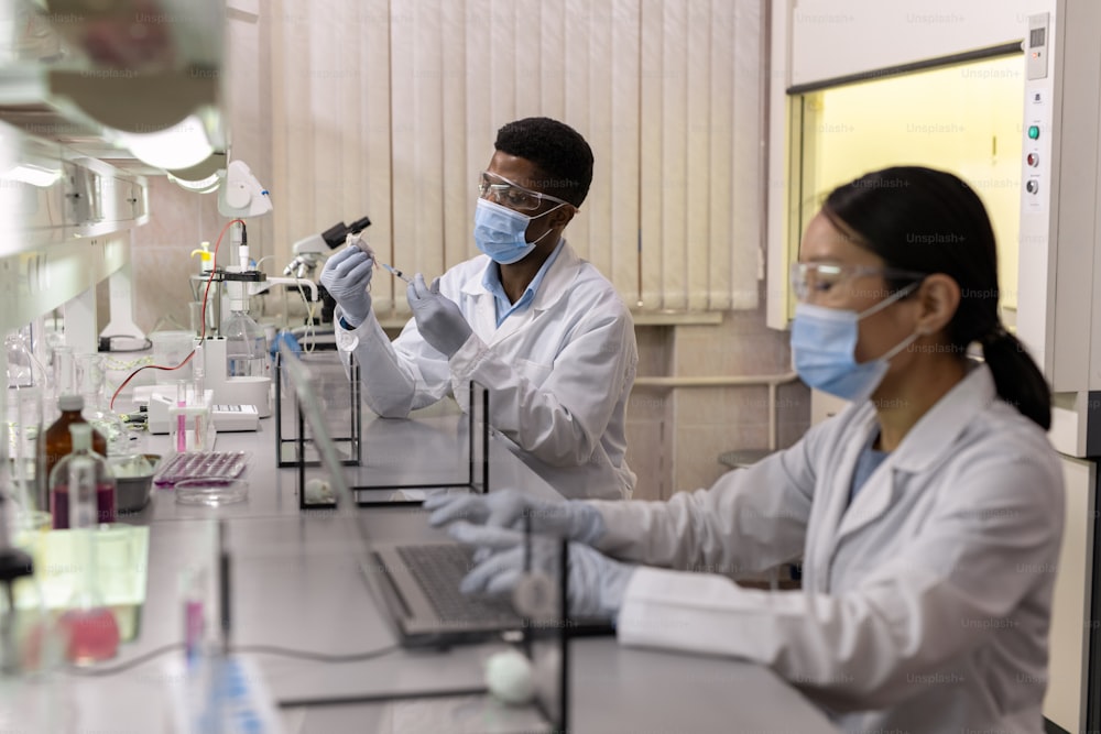 실험실에서 새로운 백신을 테스트하는 흰 쥐를 가진 화학자 중 한 명