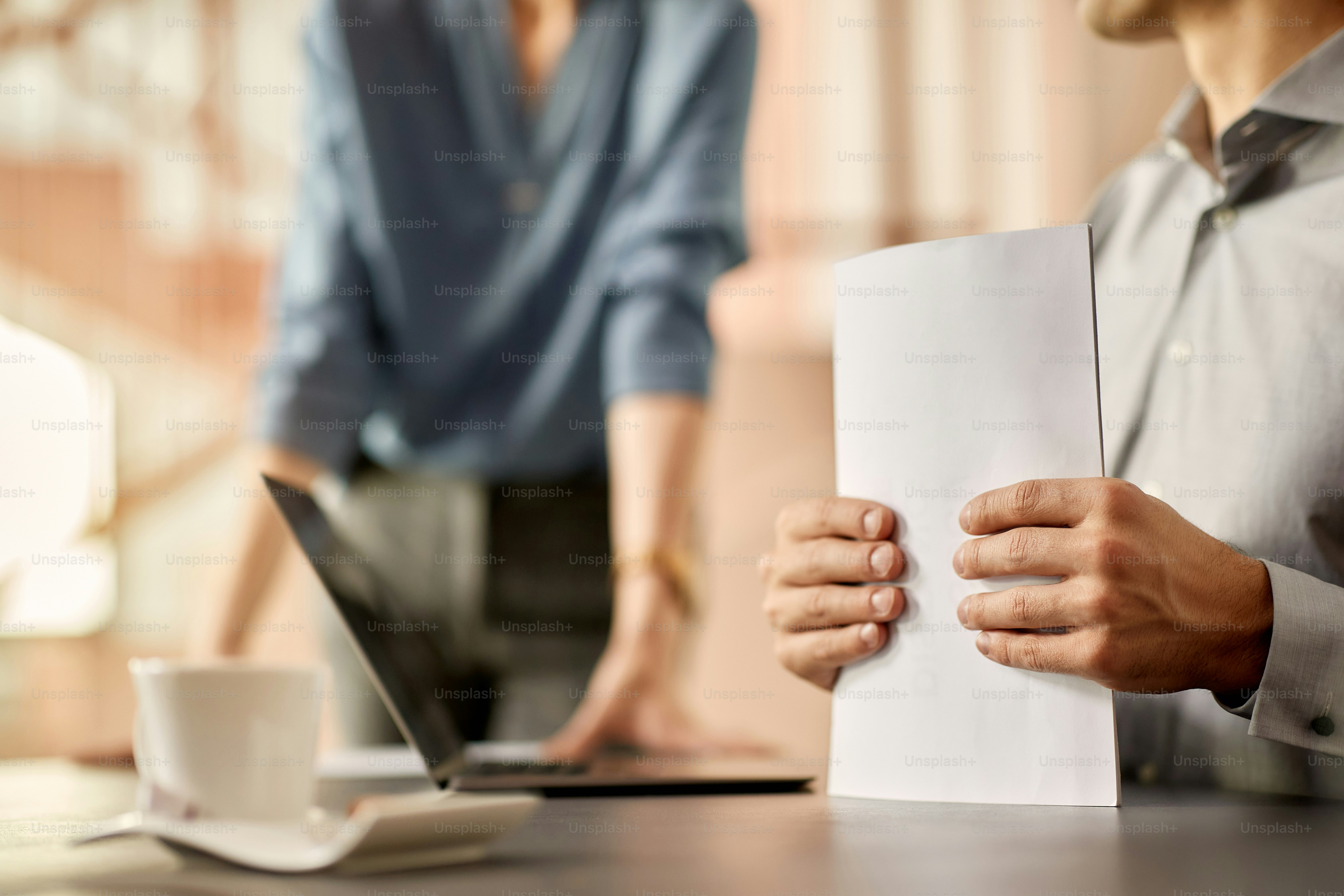 Close-up of businessman holding paperwork while having a meeting in the office.