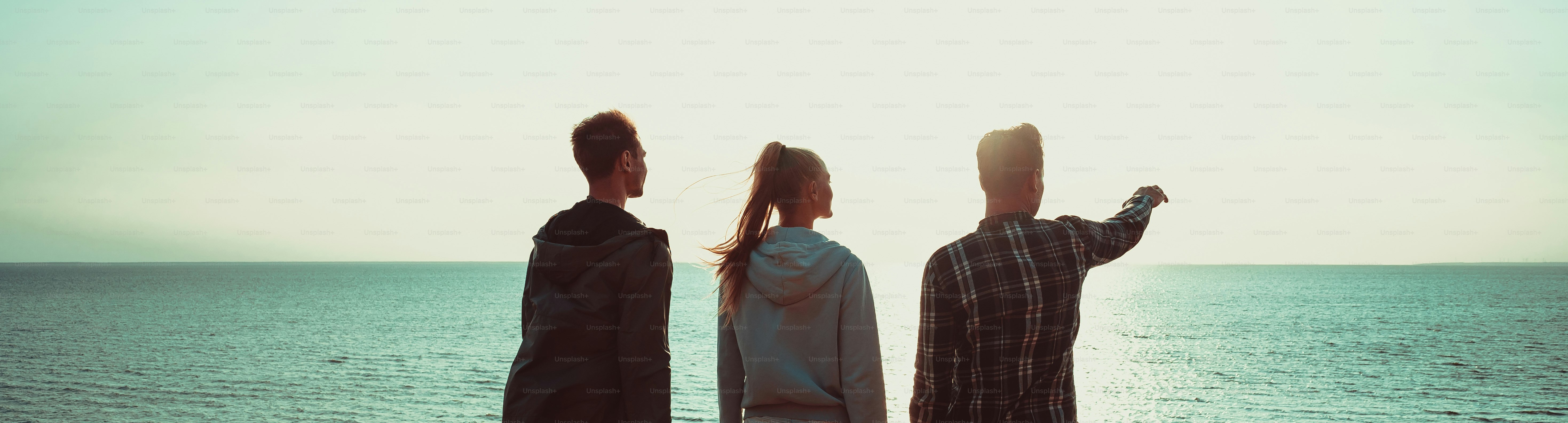 The three people standing on the mountain top near the sea