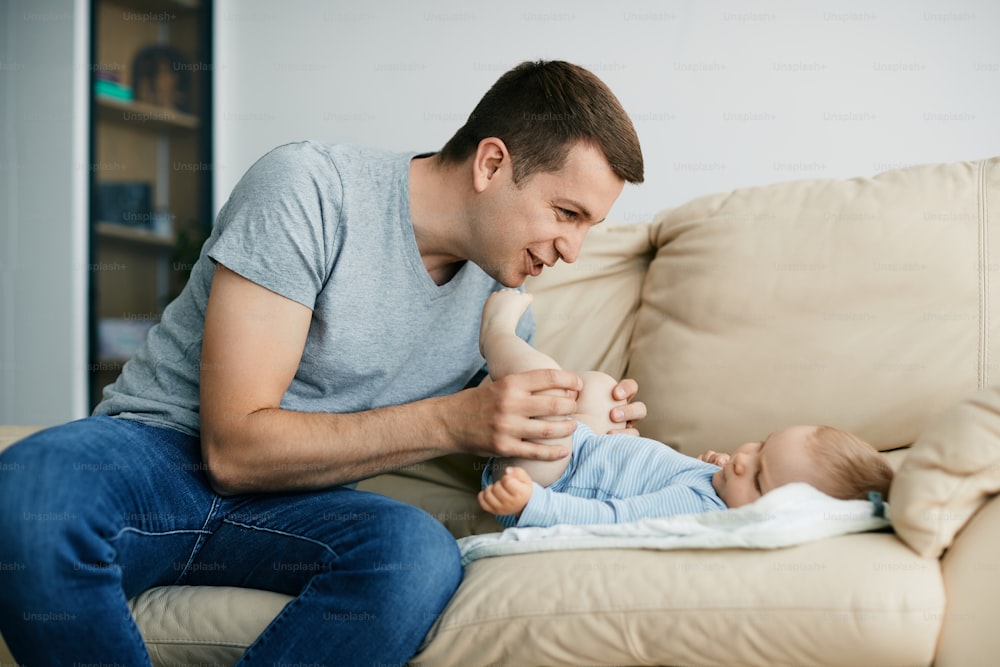 Young father having fun while spending time with his baby boy in the living room.