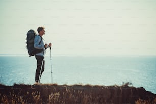 O viajante com mochila em pé no topo da montanha acima do mar