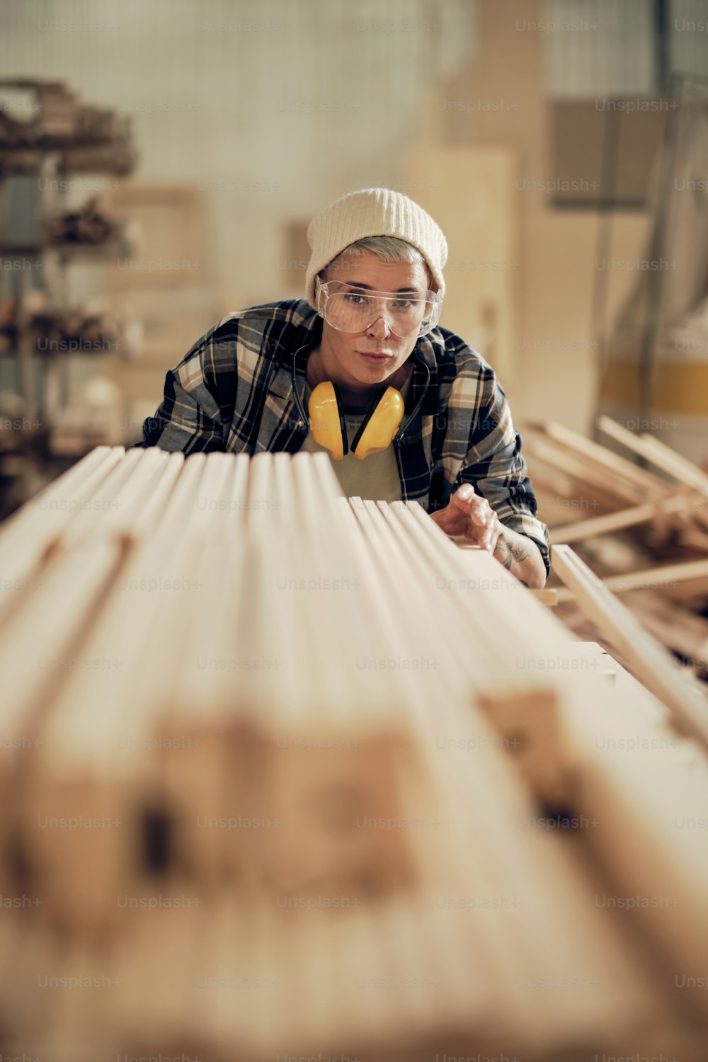 Retrato do carpinteiro feminino nivelando a pilha de madeira das tábuas, trabalhando na carpintaria