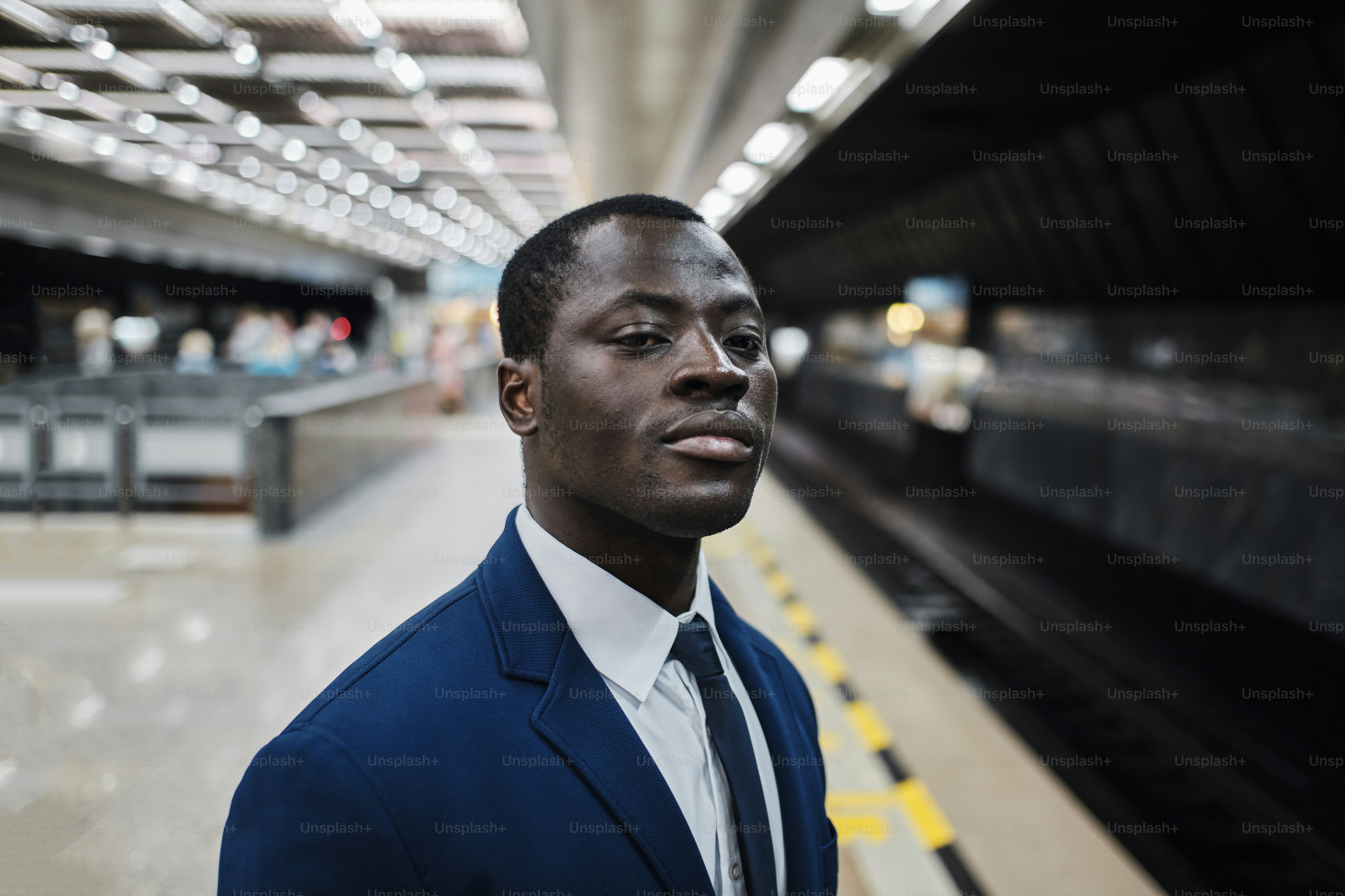 Ritratto di uomo nero fiducioso sorridente che indossa abito e cravatta blu  alla stazione della metropolitana, sta guardando il tunnel, in attesa  dell'arrivo del treno foto – Immagine di Azienda su Unsplash, image size:3000x2000