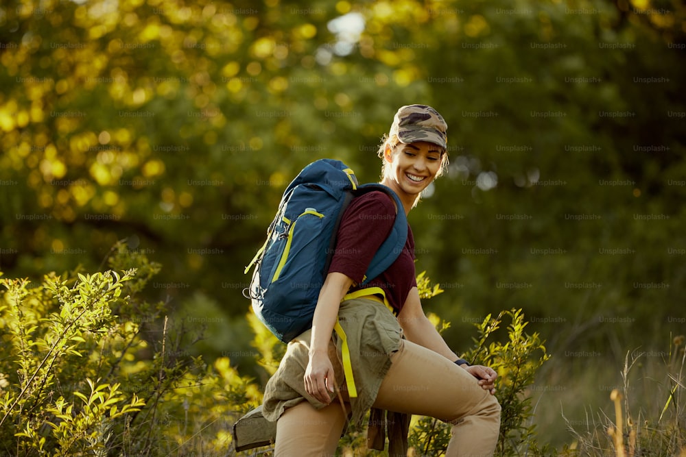 Junge glückliche Backpackerin, die ihren Tag beim Wandern durch die Natur verbringt.