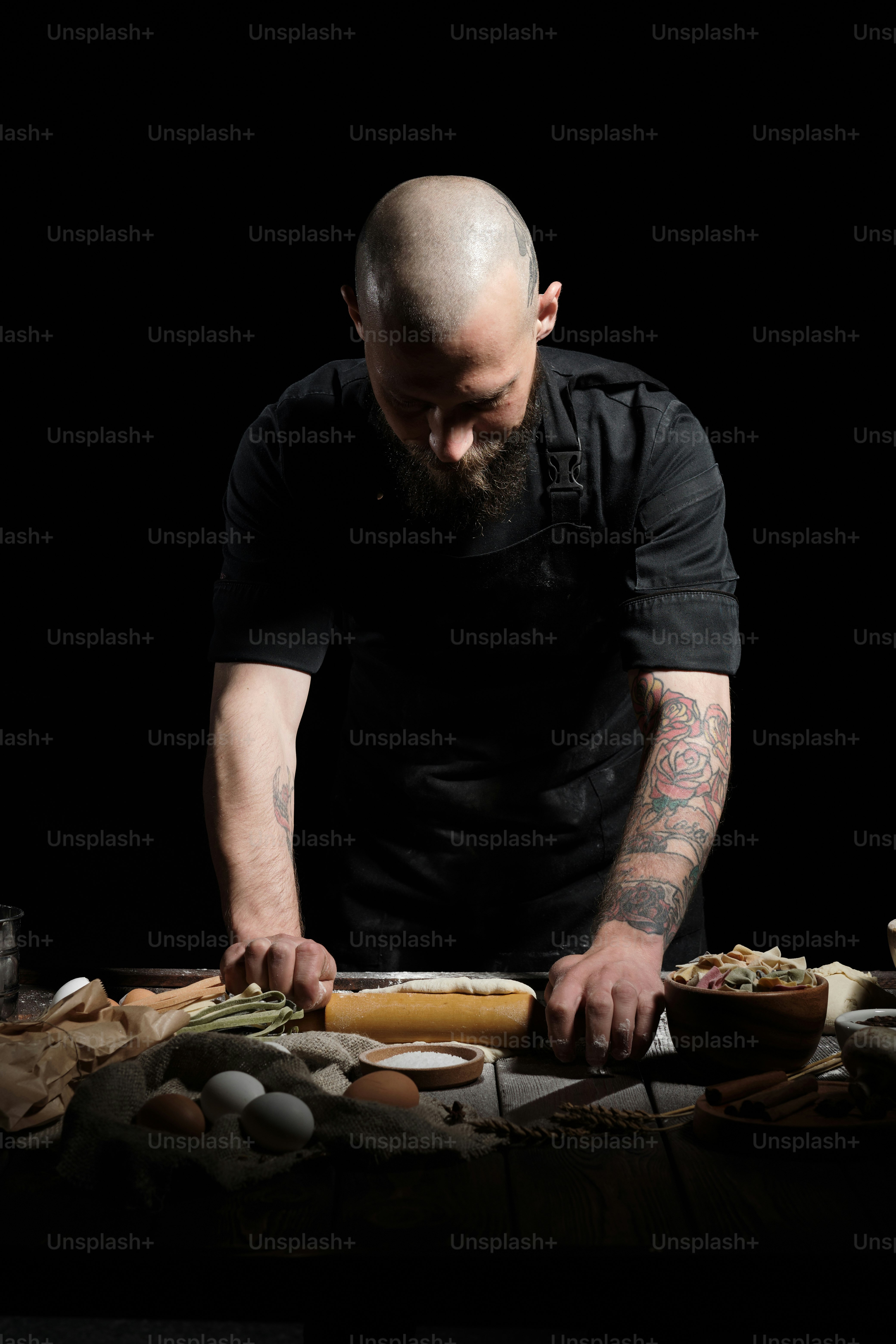 Porträt des Küchenchefs im Studio auf schwarz. Er macht frischen Teig