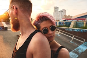 Retrato da menina de cabelos cor-de-rosa e do homem de auburn juntos ao ar livre. Ela está apoiada em suas costas, confiança e conceito de confiança