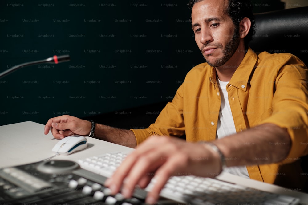 전문 녹음 스튜디오에서 무대 믹서 컨트롤러를 사용하는 노란색 셔츠를 입은 모로코 남자의 초상화
