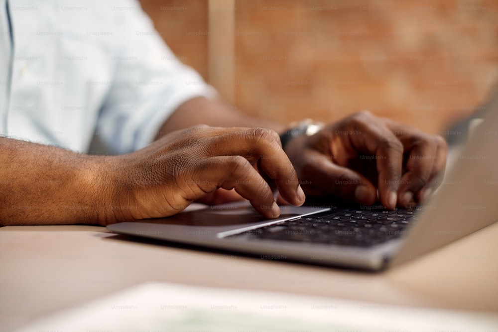 Primo piano dell'uomo d'affari afroamericano che lavora sul laptop in ufficio.