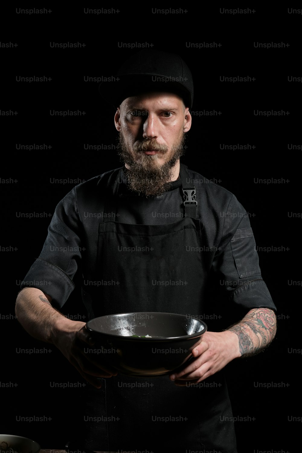 Retrato de un chef masculino brutal sosteniendo un plato con comida recién hecha en un tazón