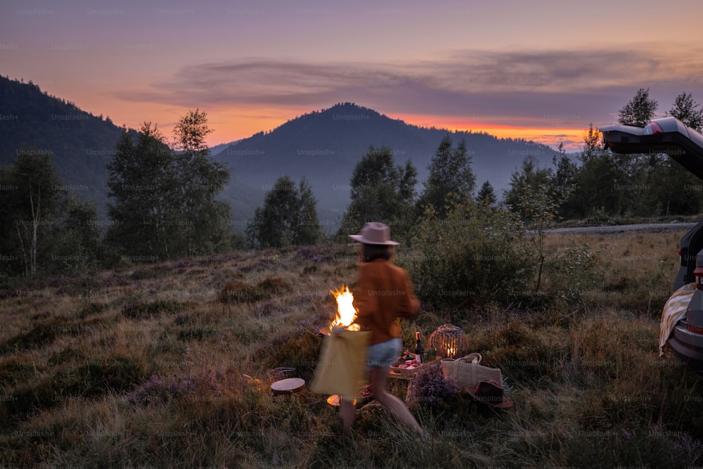 Hermoso picnic con hoguera y persona borrosa de movimiento caminando en las montañas al anochecer