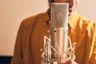 Close up of moroccan man in yellow shirt singing with microphone in professional recording studio