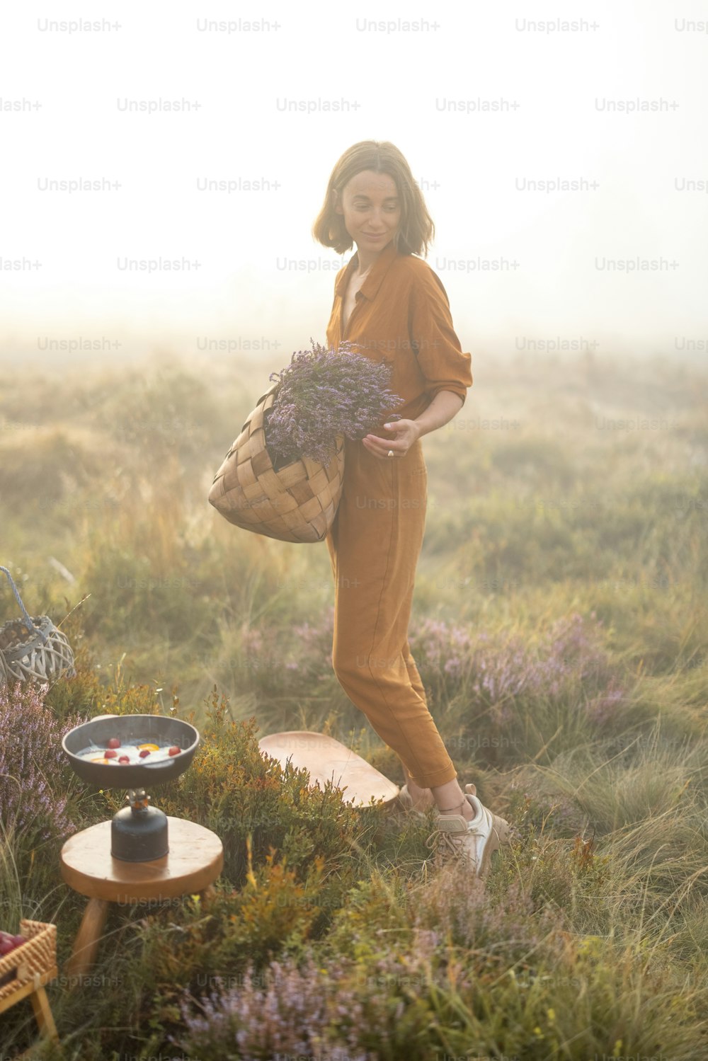 Portrait of a cute woman with a freshly picked up heather bouquet in the mountains in a foggy weather