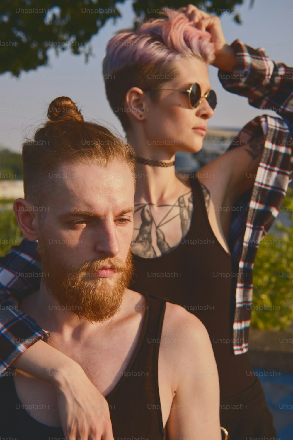 Close up portrait of a hispter couple, girl with punk hair in round glasses hugging and kissing auburn bearded man