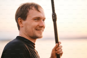 Portrait of a strong man with paddle getting out of water after swimming