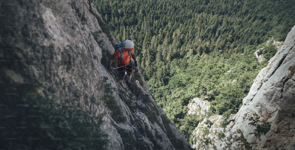 Climber on via ferrata trail, crossing a steep mountain edge.