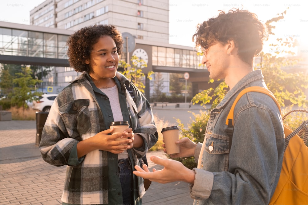 Two students of college having drinks after classes in urban environment