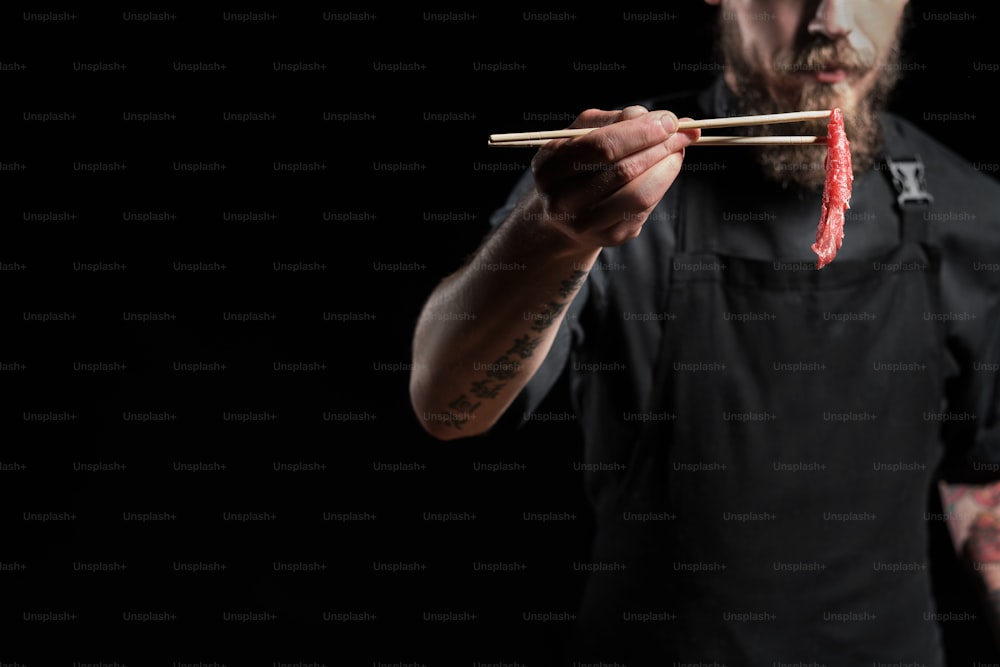 Close up of chef holding beef piece with chopsticks, cooking fresh asian dish