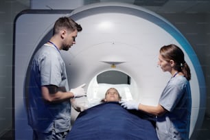 MRIスキャン装置で検査前に小さな患者を診察する2人の放射線科医のうちの1人