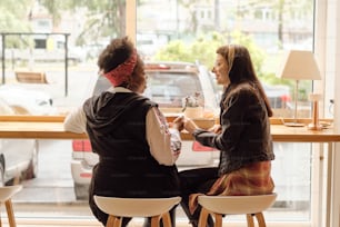 카페에서 창문 앞에서 점심을 먹는 동안 h와 hs를 들고 있는 행복한 젊은 레즈비언 커플