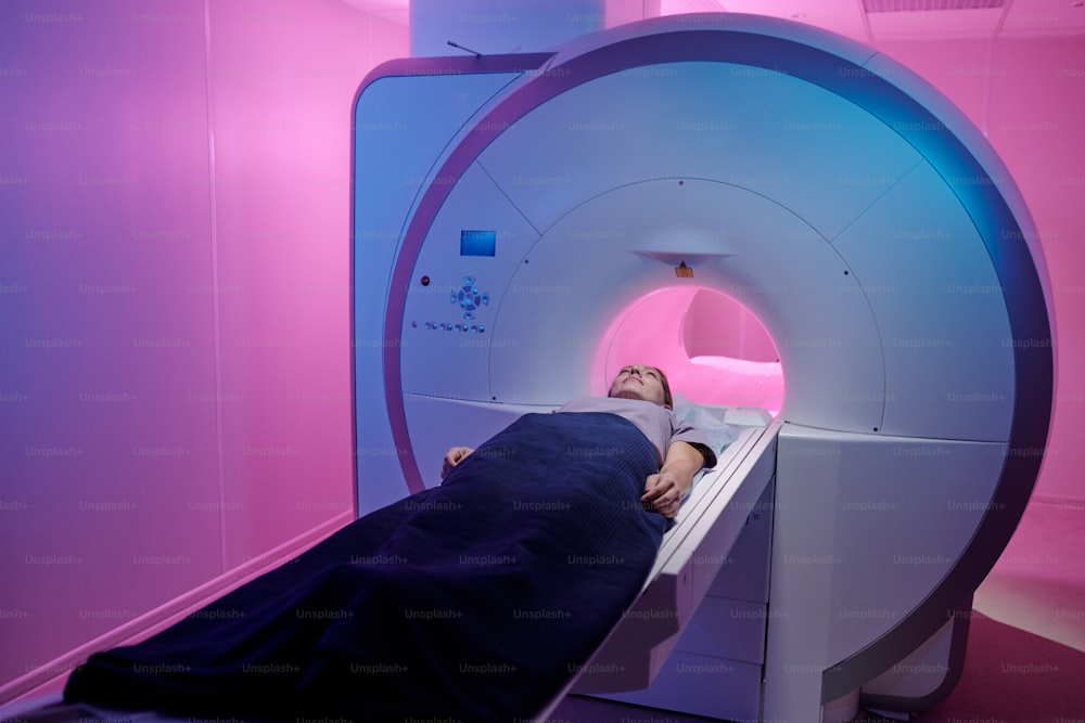 Mujer enferma joven que se somete a un procedimiento médico en una máquina de exploración de resonancia magnética en clínicas