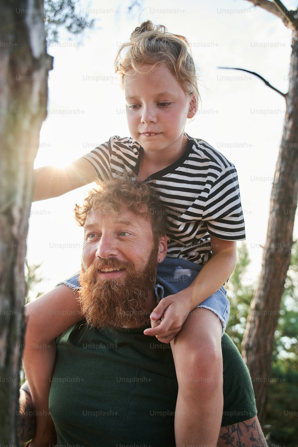 My sweet. Waist up portrait view of the happy man holding at the shoulders his little daughter while enjoying of the good day at the open air. Stock photo