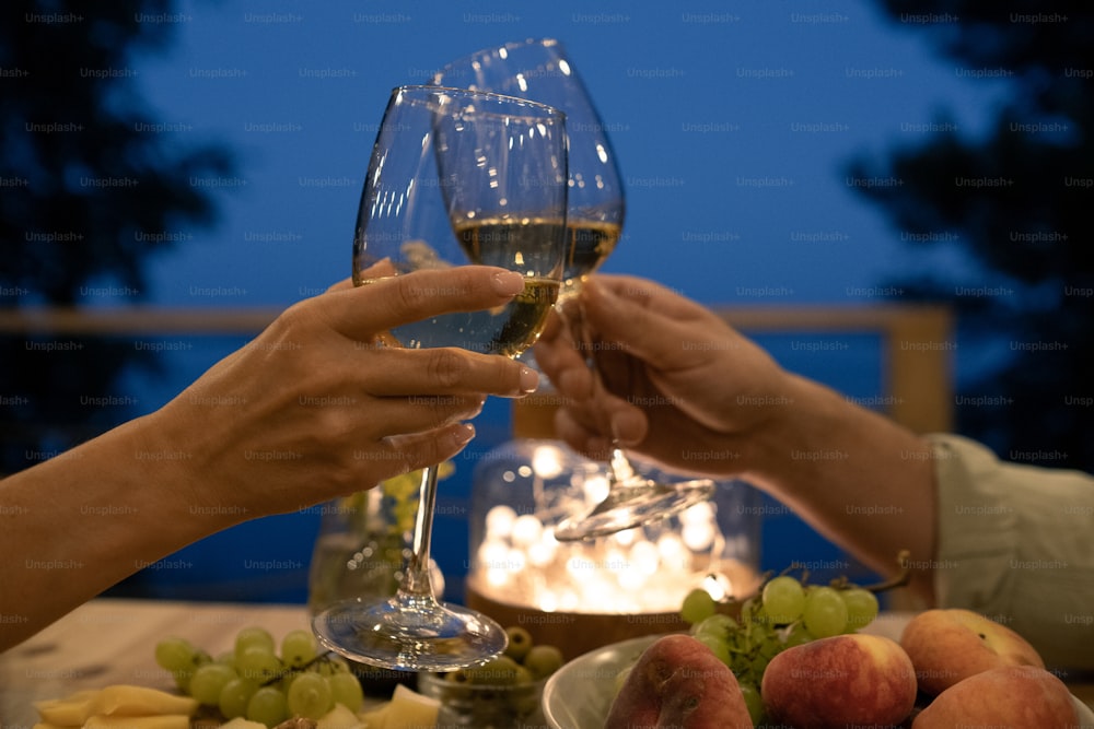 Young man and woman toasting over served table during outdoor romantic dinner