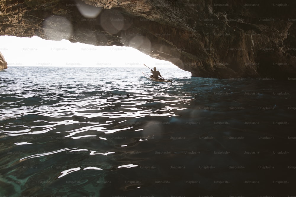 Vista traseira do homem remando caiaque em uma caverna. Caiaque e espeleologia ao mesmo tempo.