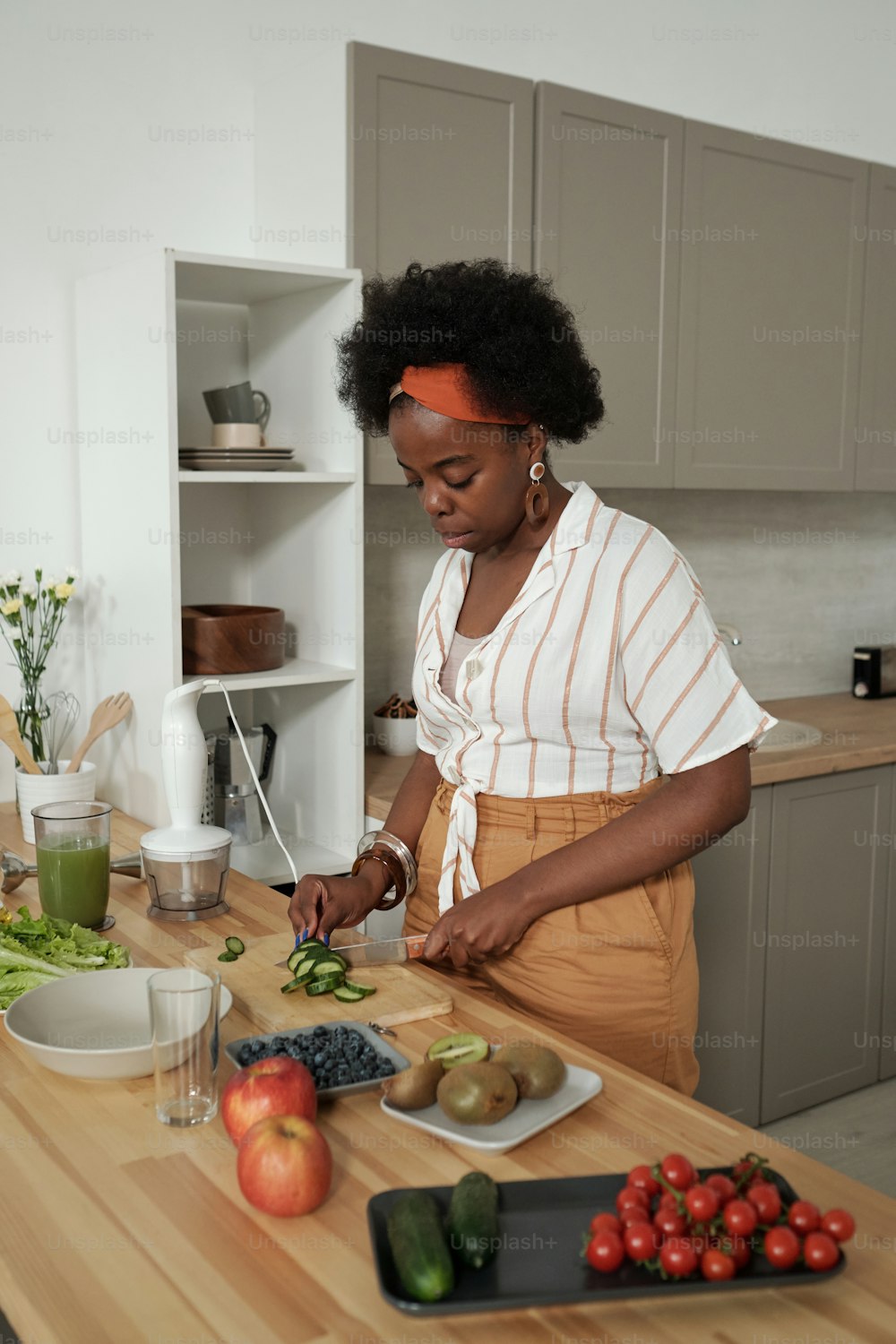 Young housewife chopping fresh vegetables for salad by kitchen table