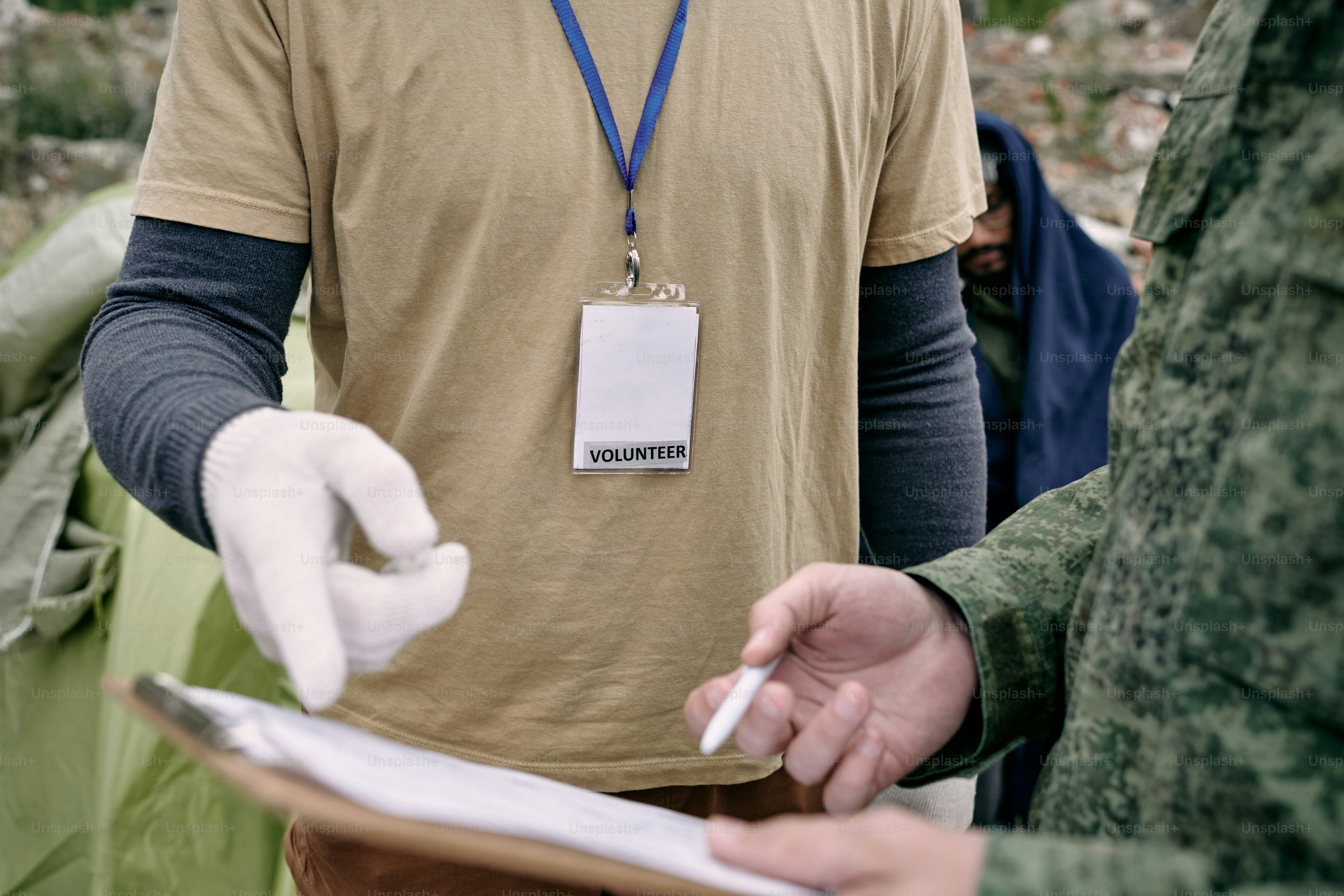Aid workers using tablets to record service locations in a crowded refugee settlement