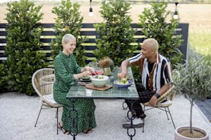 Multiracial couple eating organic food at dinner outdoors. Concept of relationship. Idea of healthy eating. Modern domestic lifestyle. Black man and european woman enjoying time together