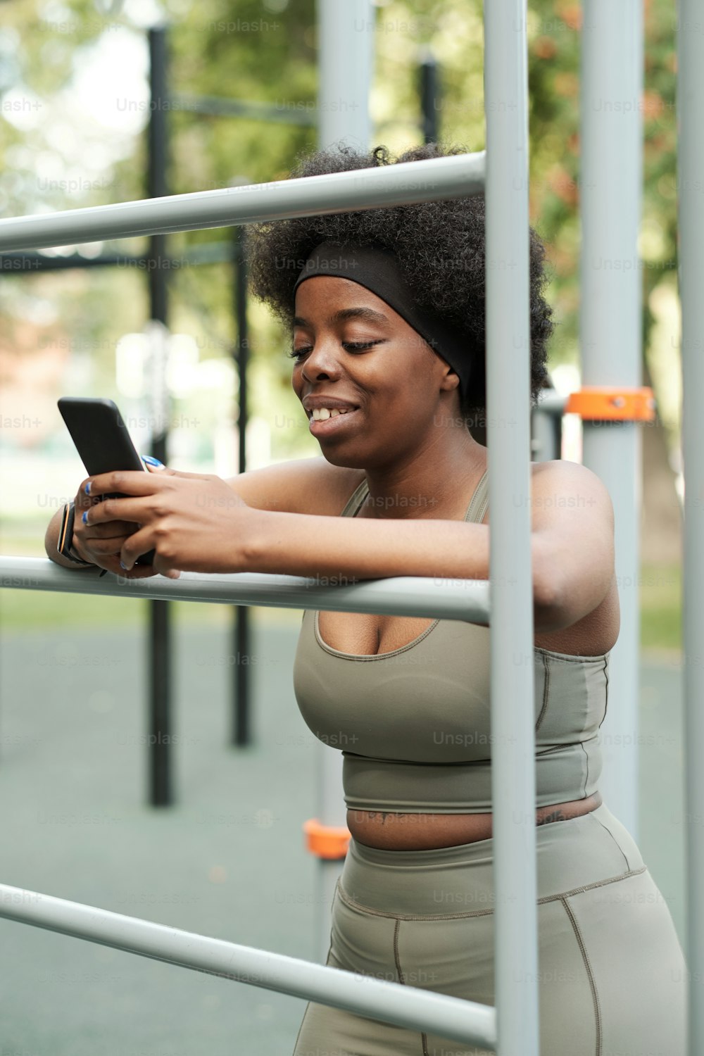 Young smiling female in sportswear scrolling in smartphone at break after hard training