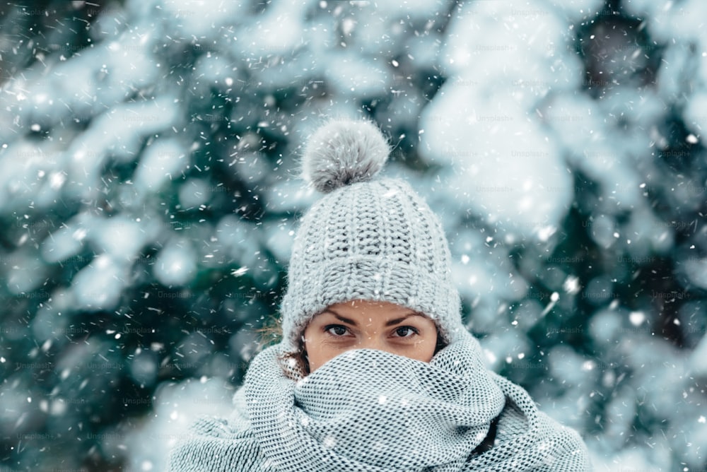 Porträt einer schönen jungen Frau mit Schal und Hut an einem kalten Wintertag bei Schnee