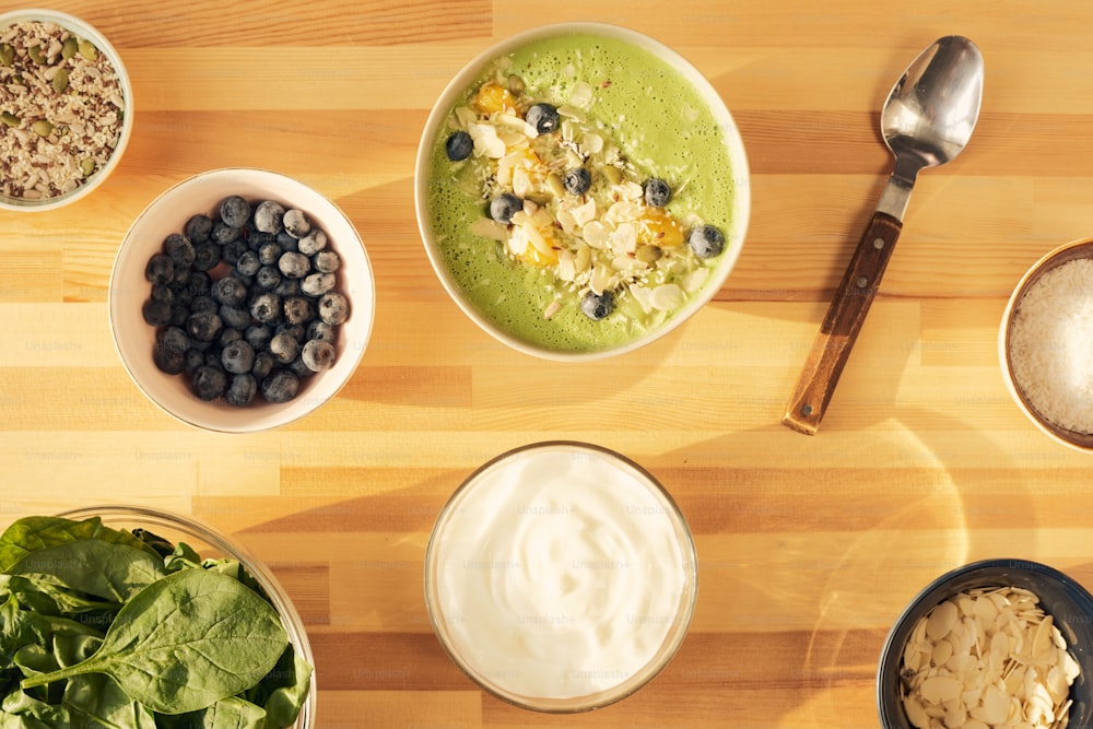 Layout of fresh ingredients of smoothie in large bowl decorated with blueberries, almond flakes and pumpkin seeds