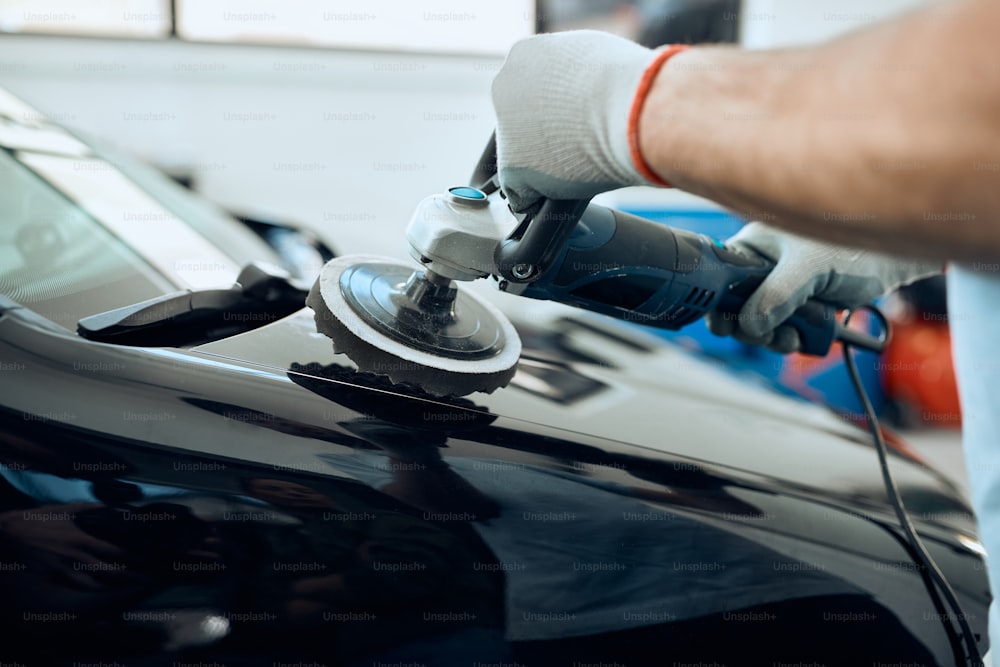 Close-up of man polishing car while working at auto service workshop