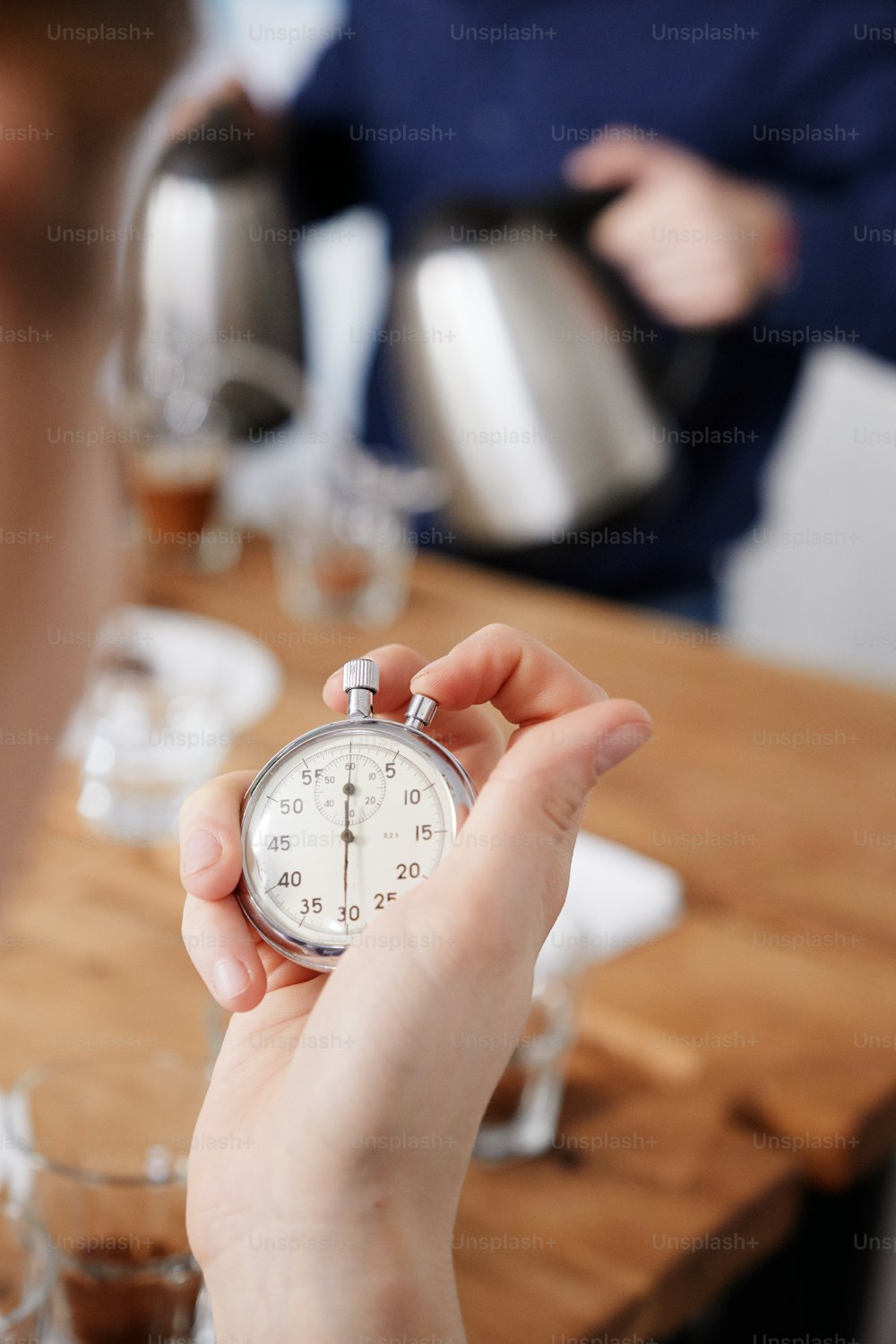 Close up of female holding stopwatch, measuring time for brewing fresh coffee in cups