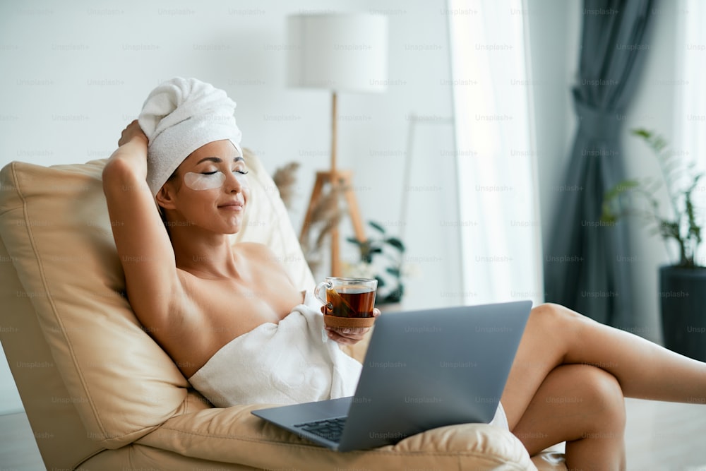 Young woman with under eye patches drinking detox tea and relaxing with eyes closed at home.